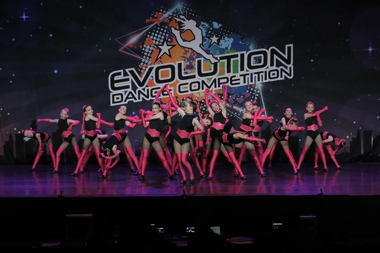 JMDS troupe in pink and black performing on stage at the Evolution Dance Competition