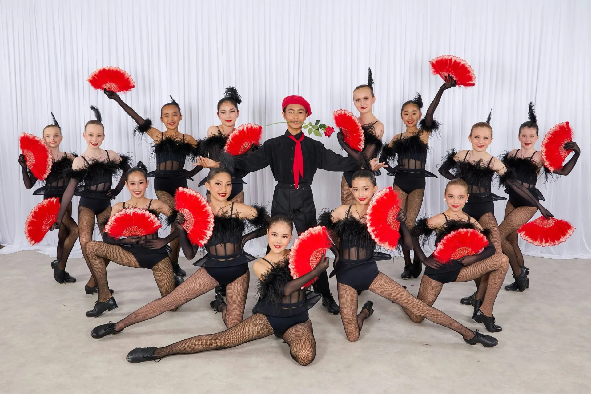 JMDS troupe in black feathers and fishnets with red fans